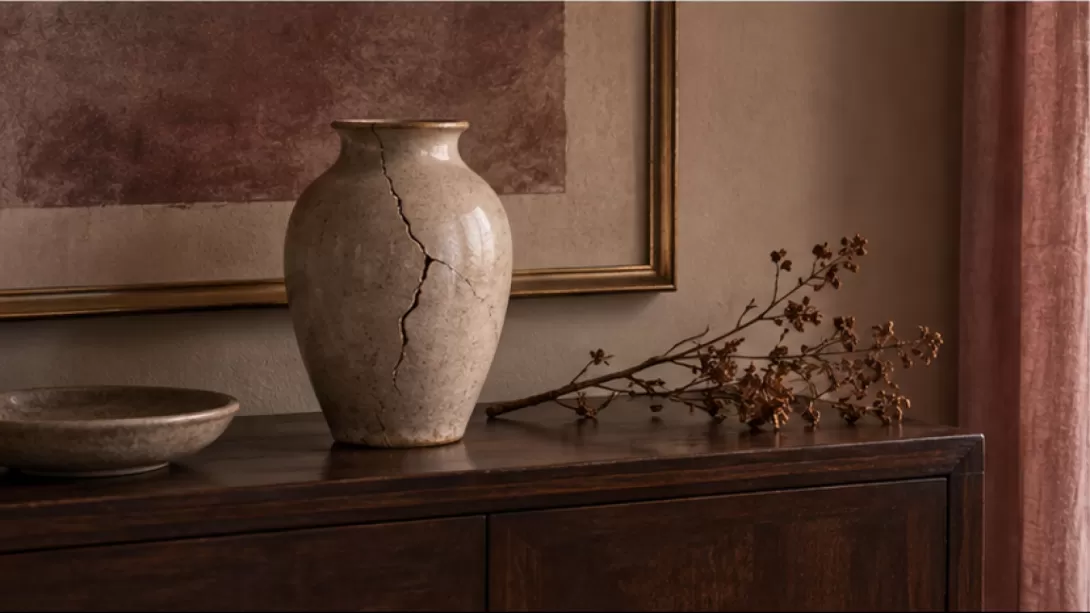 Jarron de ceramica agrietado junto a una rama seca